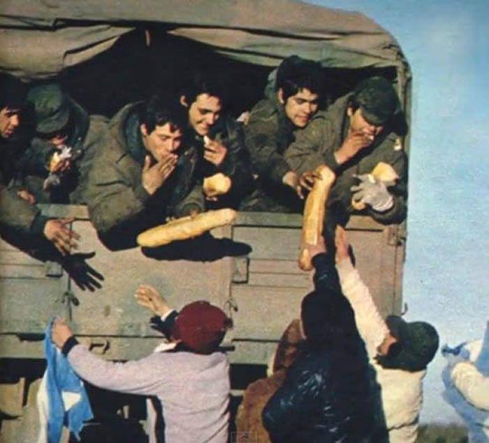 desde arriba de un camión soldados reciben pan que les pasan personas